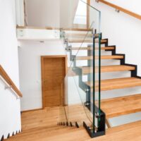Freitragende Vollholz-Treppe aus massivem Eichenholz mit Glasgeländer in einem hellen Wohnhaus