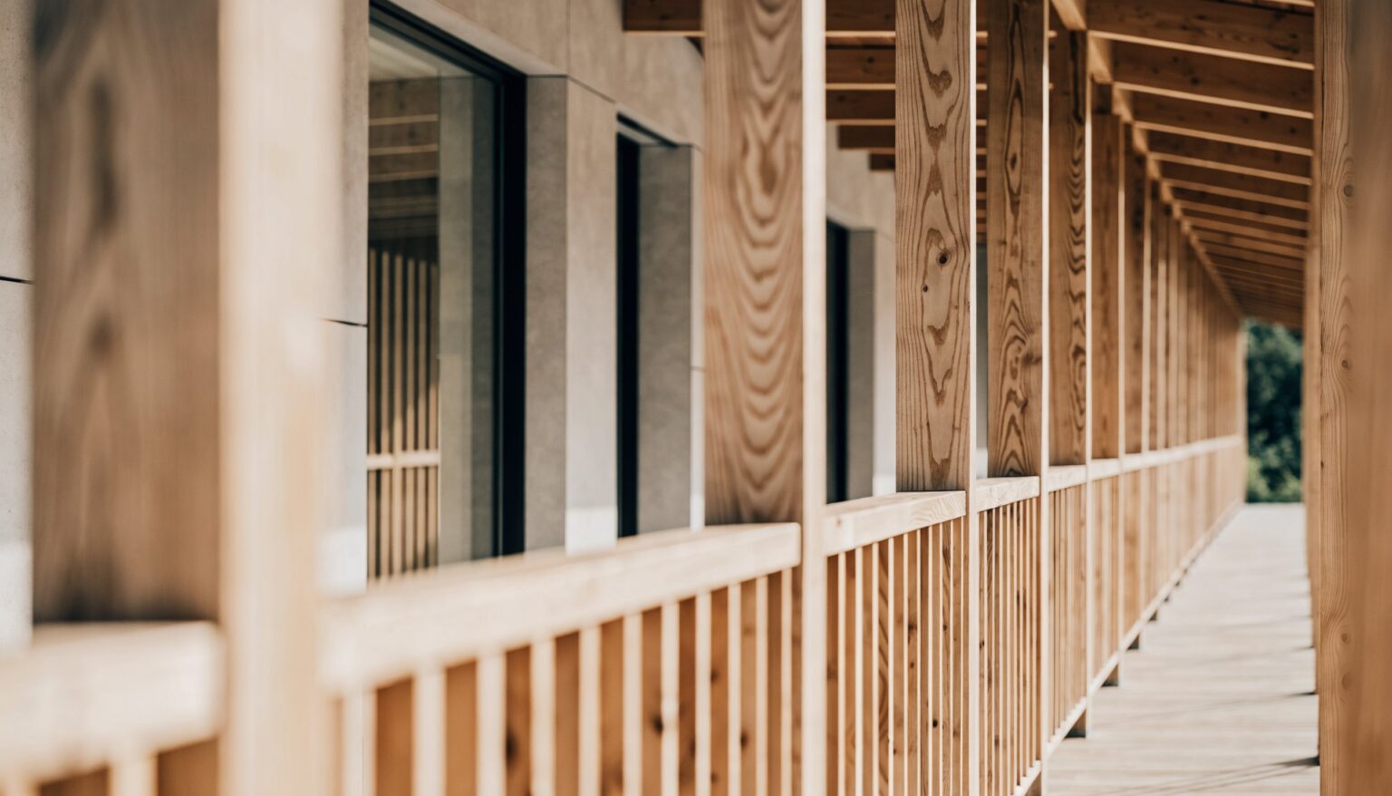 Hölzerner Laubengang mit Pfosten, Balken und Holzgeländer an einem Haus – Holzkonstruktion und Geländer