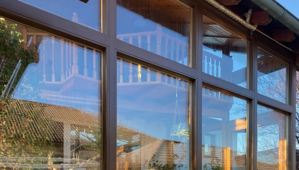 Sanierte, anthrazit verkleidete Fenster- und Wintergarten-Front eines Hauses – KANOVA Fenstersanierung von Steinkogler