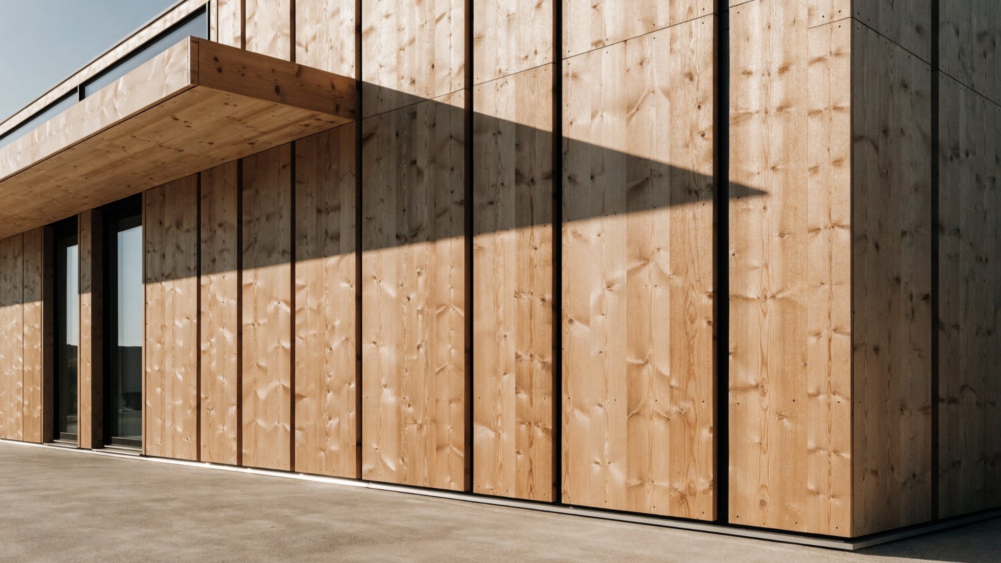 Fassade aus senkrechter Lärchenschalung mit Dachvorsprung, Beispiel für Lärche an der Hausfassade