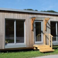 Tiny-Haus aus Vollholz: HoizHoamat von Steinkogler mit Holzfassade, großen Fenstern und Holzstiege
